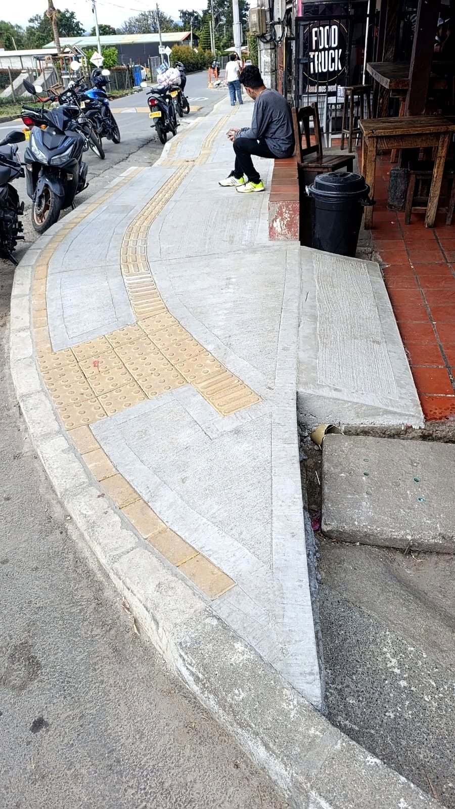 Loseta táctil guía y alerta siguiendo una curva en esquina de andén en concreto